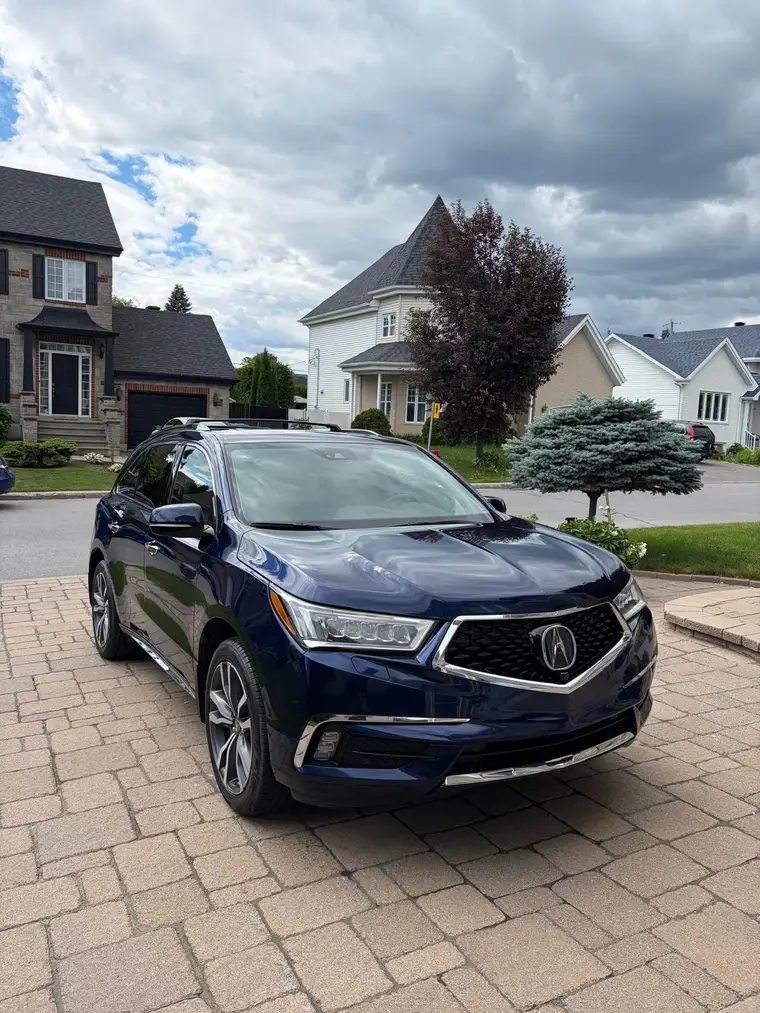 Navy blue Acura MDX detailed on a paver driveway