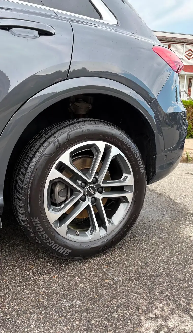 Audi Q3 wheel with fresh tire dressing after a wheel detail