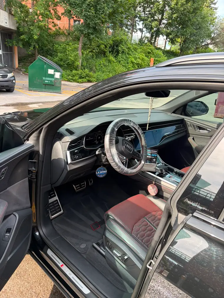 Audi RS Q8 interior with red and black sport seats, steering wheel wrapped for delivery