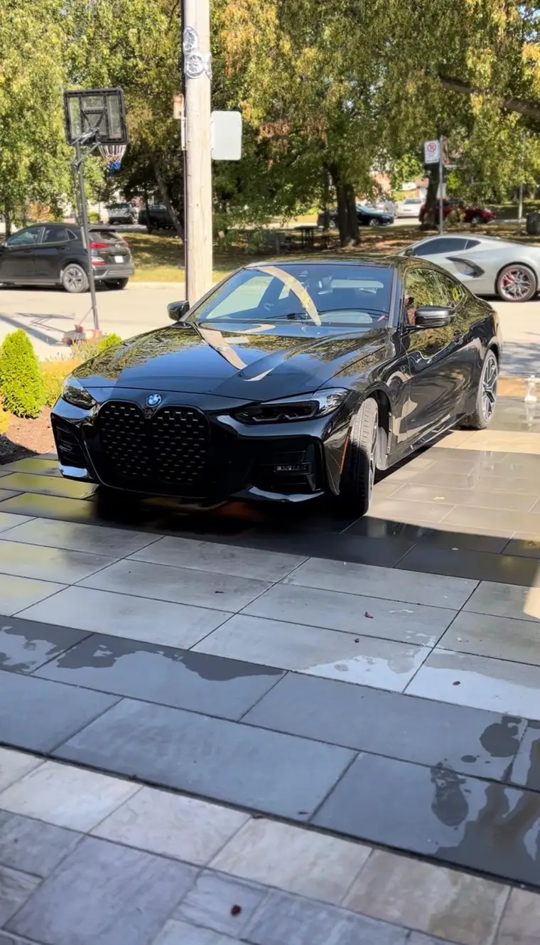 Black BMW 4 Series coupe on wet pavers after a full wash in Montreal