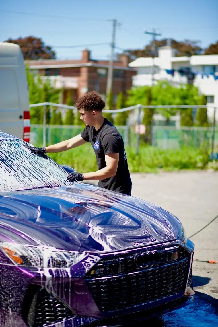 Hand-washing the windshield and hood of a foamed Audi RS6